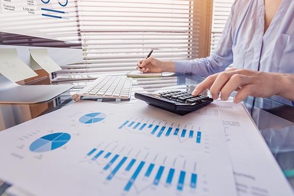 person working with a computer, calculator and paper charts and graphs