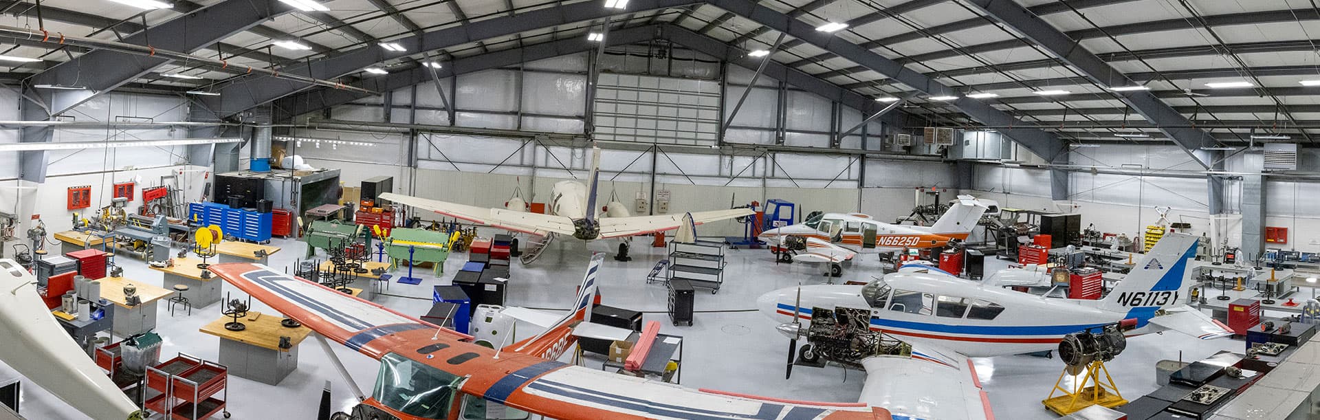 airplane hanger with several airplanes and tools