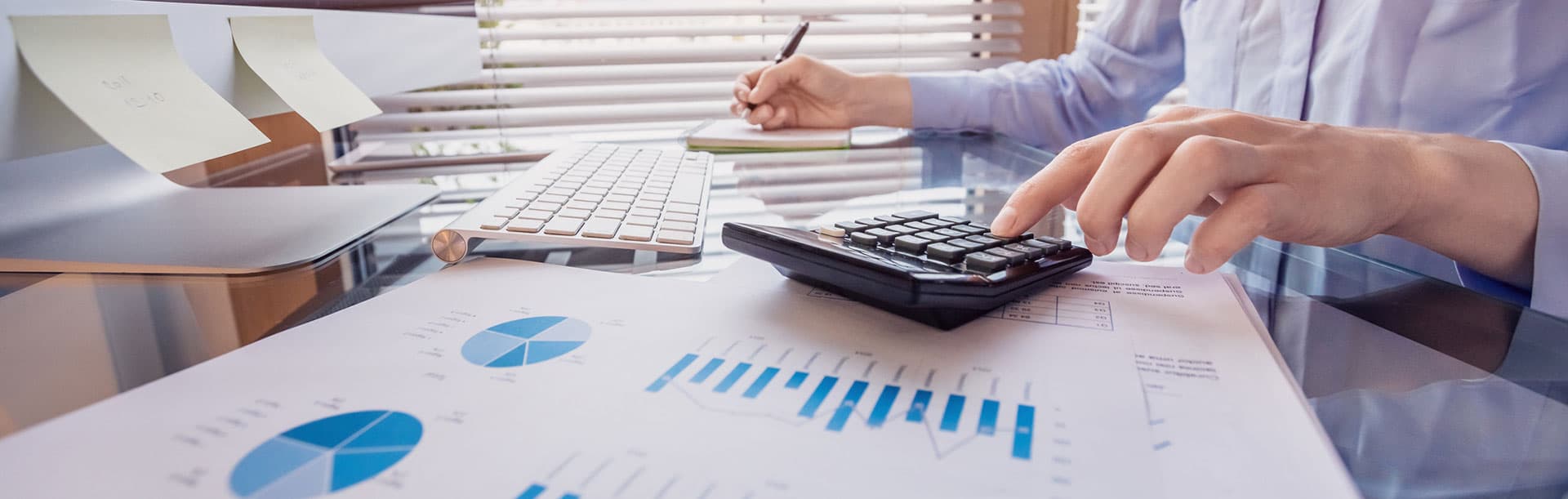 person working on computer and calculator with printed graphs