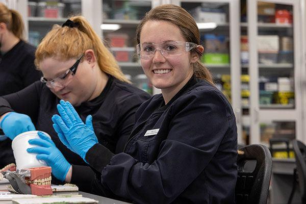 dental students wearing safety glasses and gloves working in lab class