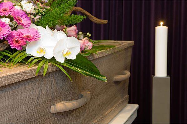 flowers on top of casket next to lit candle