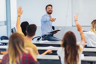 Students in a classroom raising their hands