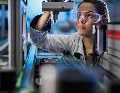 woman with goggles working on manufacturing machine