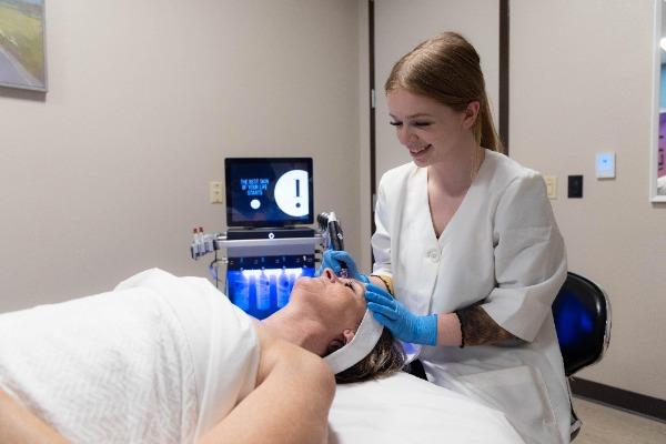 student in master aesthetician lab working with a client