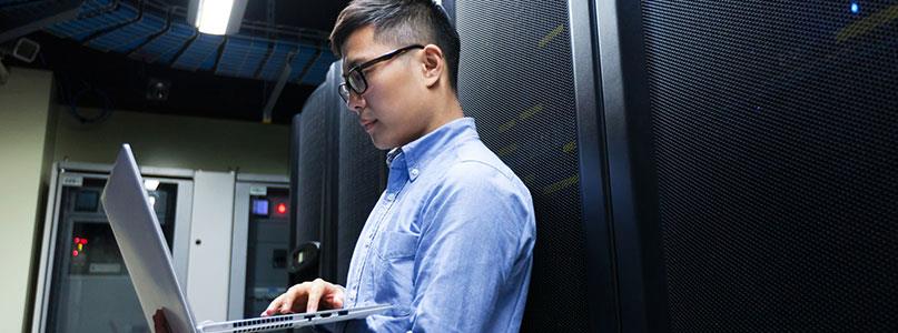 man working on laptop computer in network room