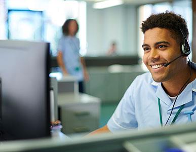 smiling person with headset on working at a computer