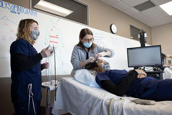 student and instructor in neurodiagnostic lab with patient