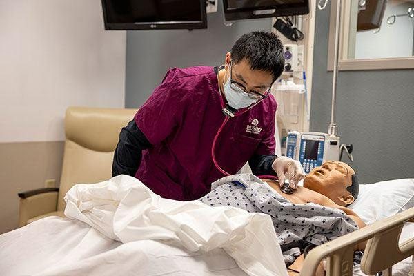 nursing student checking on a patient in a lab setting