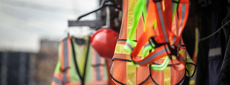 orange and yellow safety vests and helmets hanging up